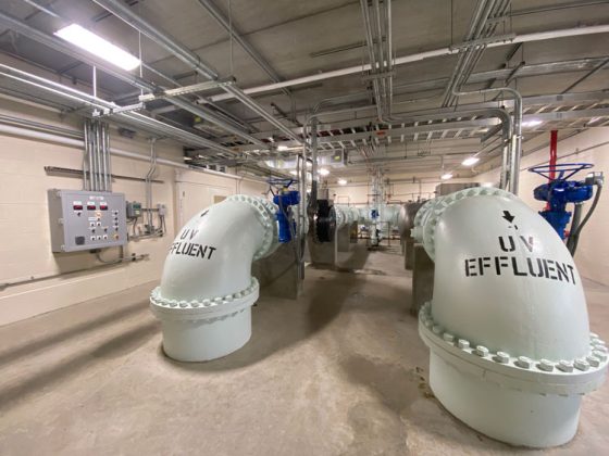 Two Large white UV Effluent pipes protrude from the floor and stretch across the inside of the large chemical UV building.