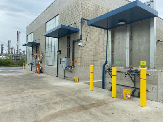 The tan brick chemical building with separate drive-up unloading areas, overhanging roofs, and chemical hose connectors.