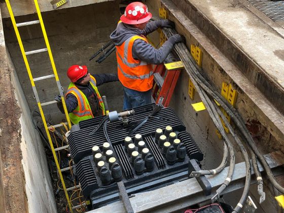 Construction workers installing electrical equipment on the roof of a city building.