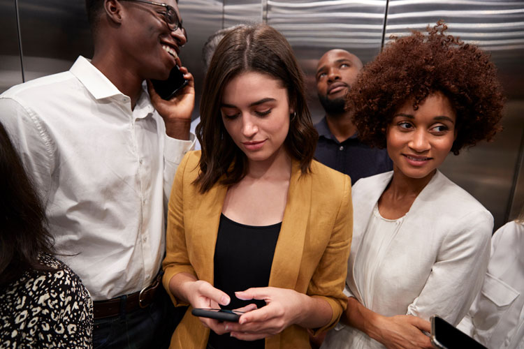 A diverse group of business people inside an elevator.