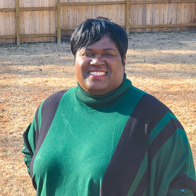 A portrait of a woman wearing a black and green sweater posing and smiling.