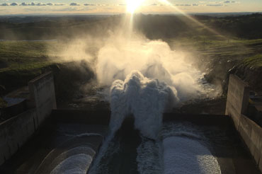 Water pouring out of a dam spillway very fast at sunset.