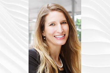 A smiling Caucasian female with long blond hair and wearing a suit jacket.