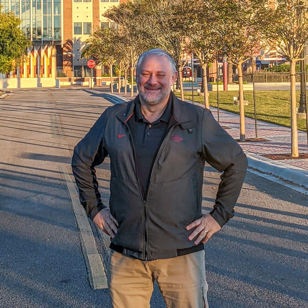 Eric Abrams, senior project manager, stands in front of the Florida State University Doak Campbell Stadium on a fall day.