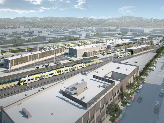 Electric rail cars parked in East San Fernando Valley LRT maintenance facility, mountains in the background, cars parked on street adjacent to facility