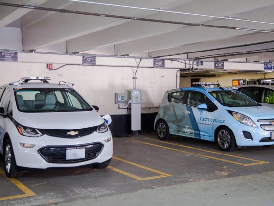 Electric vehicles are parked in spaces that are easily accessible to EV charging stations within a parking garage.