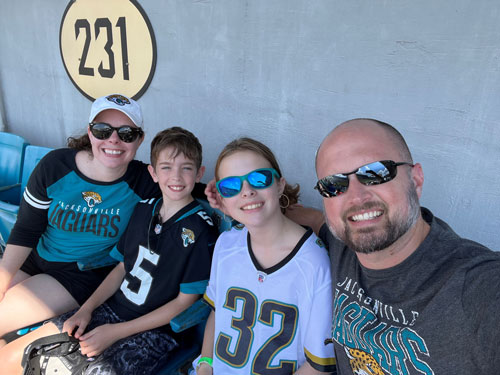 A man, woman, and two children seated in a row at a sporting event.