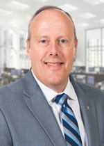 A man wearing a white shirt, blue striped tie and gray suit jacket smiling for the camera.