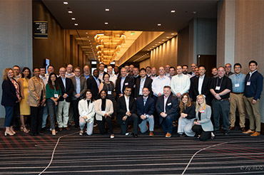 A group of people smiling for a photo at a conference hall.