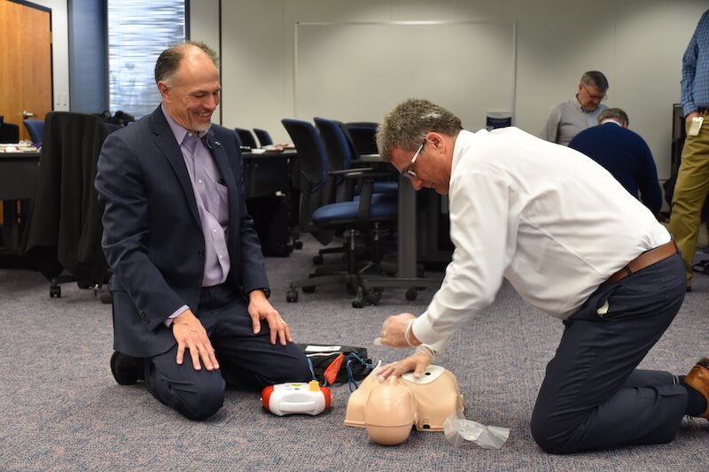 Bob Scaer and John Derr practice CPR on a dummy during training.