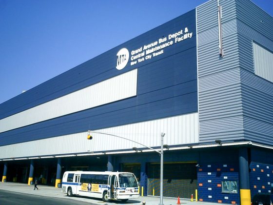 The exterior of the MTA Grand Avenue Bus Depot is blue and white. A bus is parked in front of the facility.