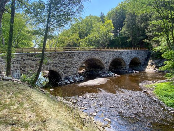 A stone arch bridge with a creek running underneath.