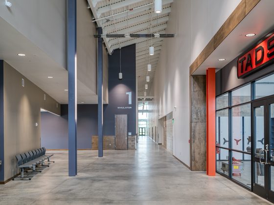 Inside of a building, facing the hallway with a seating area to the left and a room to the right.