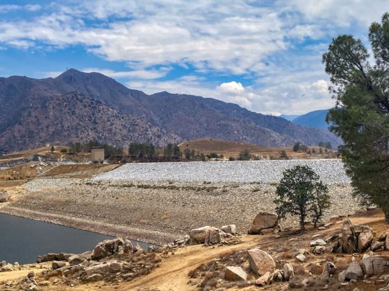 A stone-covered embankment dam surrounded by mountains.