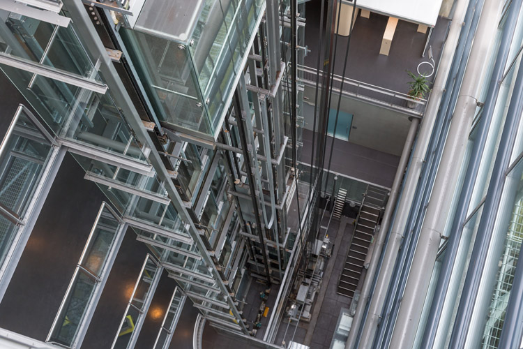 Looking downward in a modern open elevator shaft.