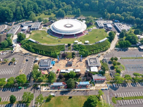 An aerial view of the circular PNC Bank Arts Center on a sunny day shows the historic open-air amphitheater and the renovated north and south plazas.