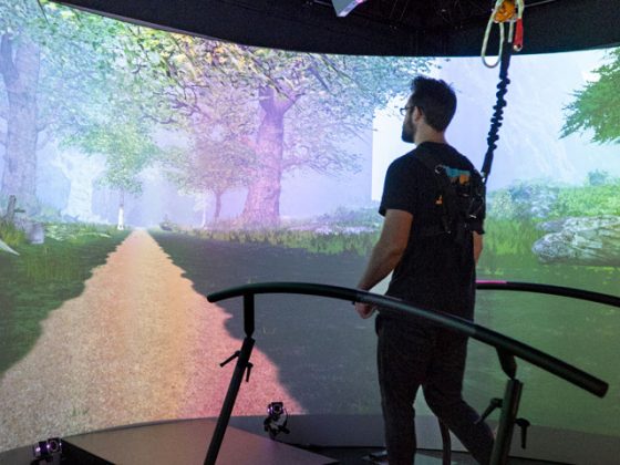 A man walking on a treadmill at Penn State’s Biomechanics Lab walks toward an image of a path projected on a screen.