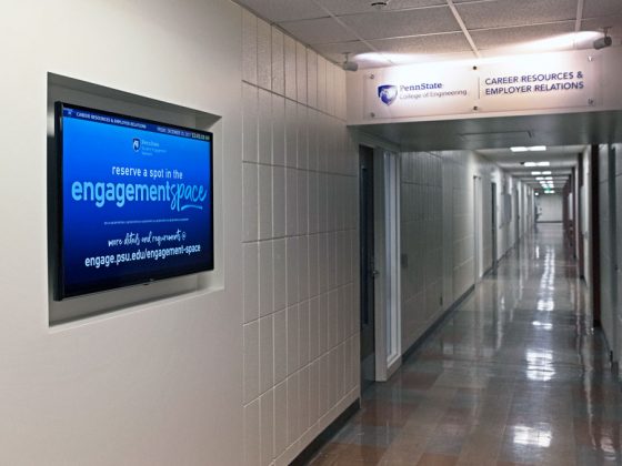 Hallway with monitor, signage, and lighting marking the doorway to an office suite.