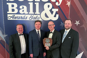 Four men posing for a photo after receiving an award.