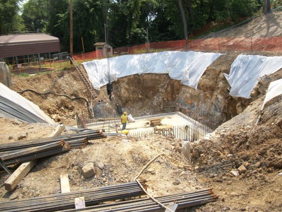 Construction worker stands on the base slab of the sequencing batch reactor, which lies inside a deeply excavated construction site.