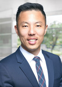 A smiling man wearing a blue suit and plaid tie.