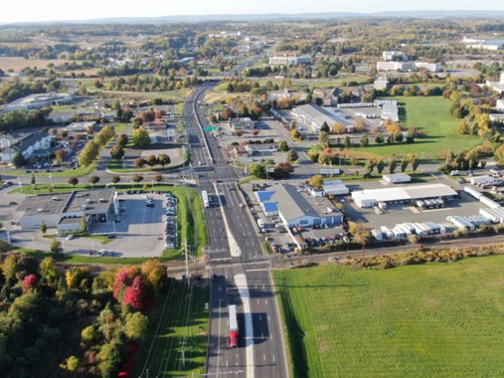 Arial view of a vertical six-lane roadway with commercial buildings along both sides.