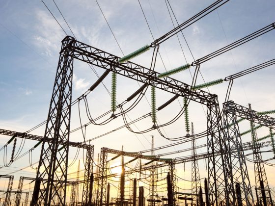 An electric power substation with wires hanging in the sky on a sunny sky.