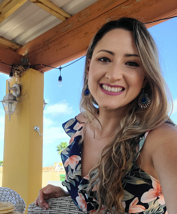 Transportation engineering expert Ister Morales smiles at the camera while wearing a flowered blouse with the blue sky in the background.