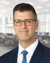 Man wearing glasses and a blue suit smiles for a portrait.