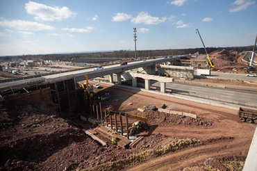 A roadway construction site with an overpass over a highway.