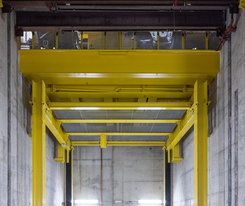 A large, cement-enclosed room with a yellow piece of repair equipment.