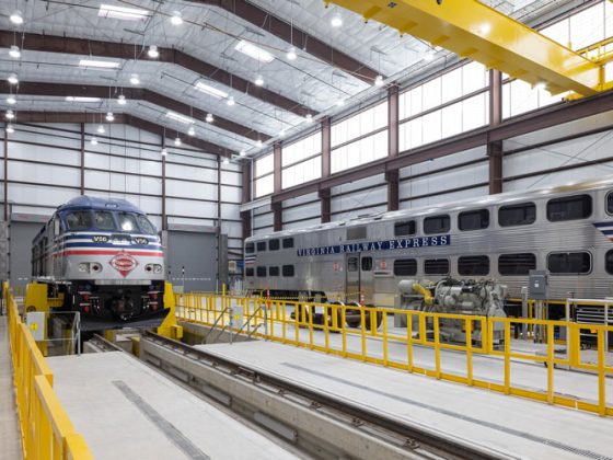 The interior of a large building with a locomotive and passenger rail car.