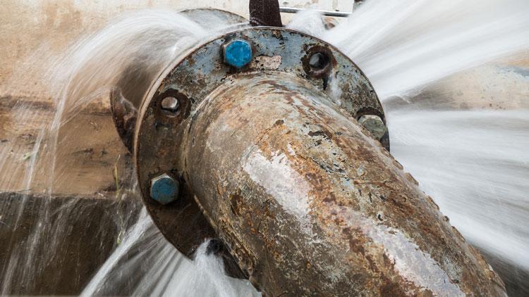 High-pressure water leak spurting from a metal pipe.