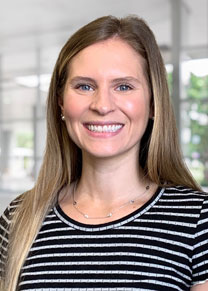 A female smiles for a headshot wearing a black and white striped shirt.