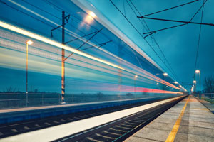 A long exposure image of train lights at dusk rushing through a train station